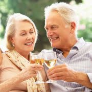Portrait Of Senior Couple Relaxing On Sofa With Glass Of Wine